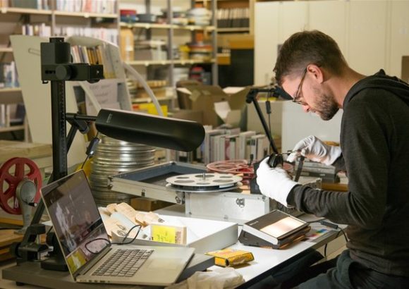 Projektleiter Pascal Werner bei der Kontrolle der Perforation und Klebestellen eines 16-Millimeter-Films im Magazin der Kantonsbibliothek. Foto: PRE